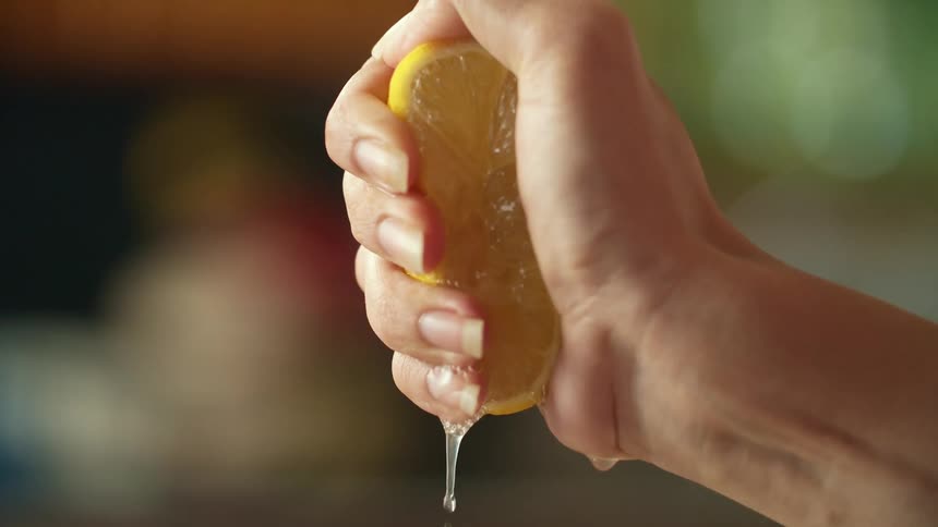 Female hand squeezing the juice from a sliced orange at home
