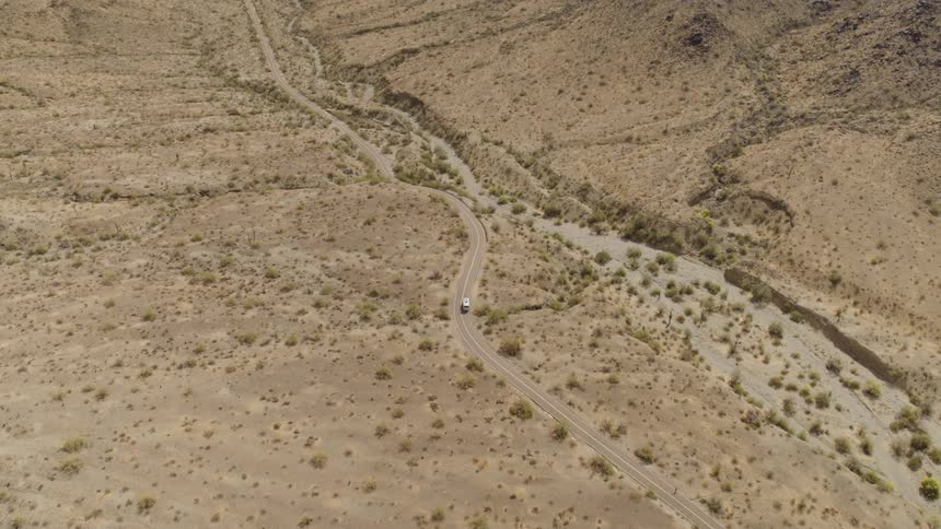 Aerial view of white van driving on highway in desert