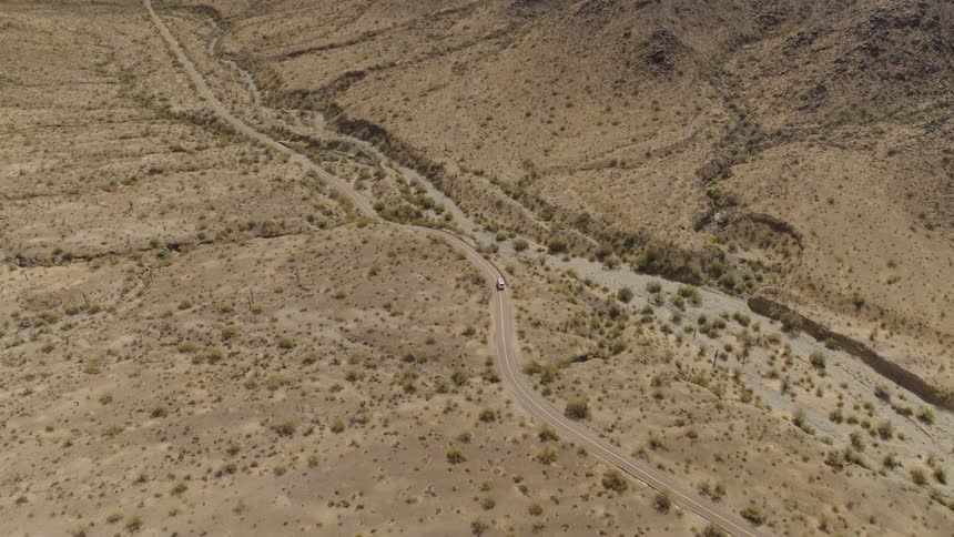 Aerial view of vehicle drives on dirt road in the desert