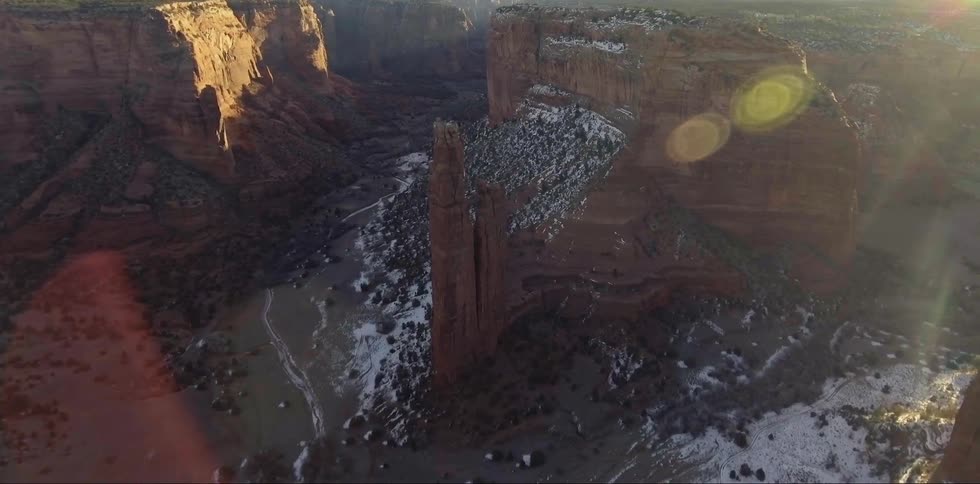 Snow settles between large rocks in the valley of a canyon