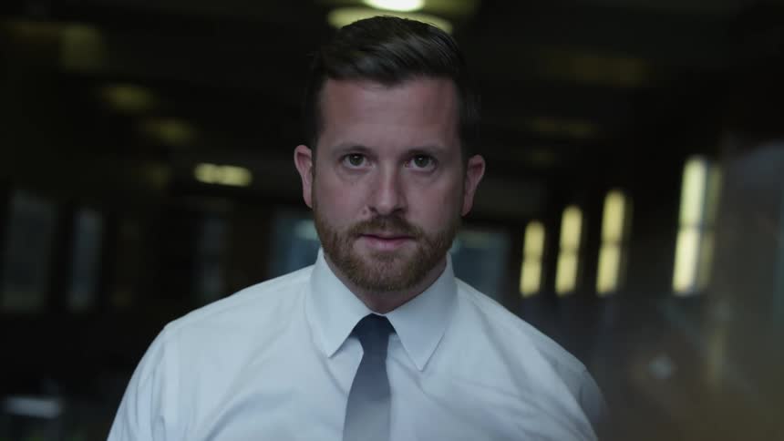 A man in a shirt and tie lifts his head and looks up