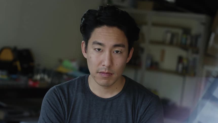 Man with gray t shirt and folded arms looking at camera in room