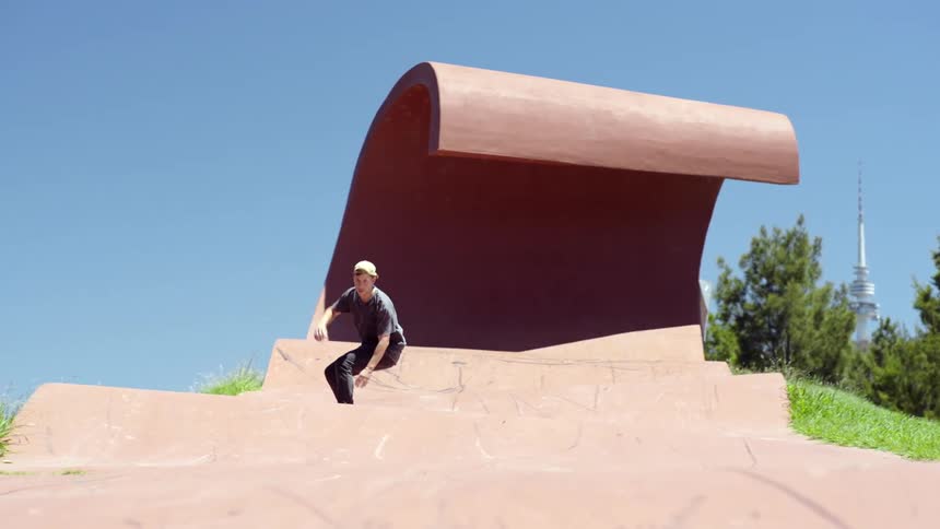 Teenager rides a skateboard down the slope of an outdoors skateboarding ramp on a park