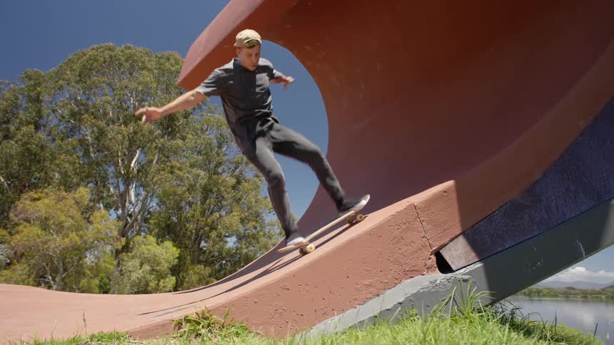 A man does a trick on his skateboard as he goes up the ramp