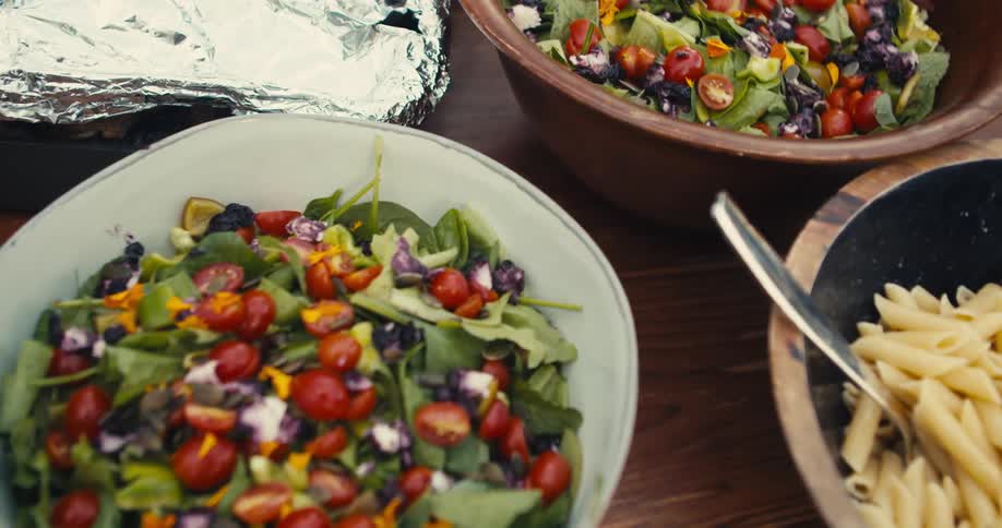 Bowls of salad and pasta over the wooden table
