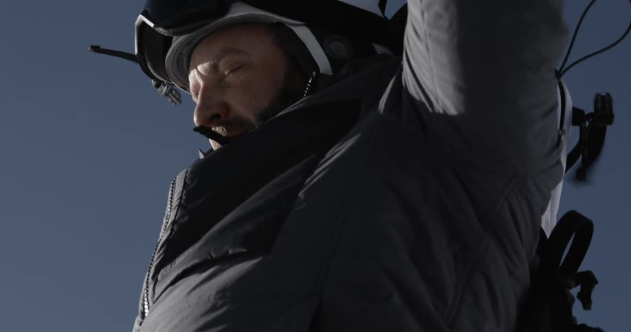 A man putting on skis and strapping on a backpack on a winter day