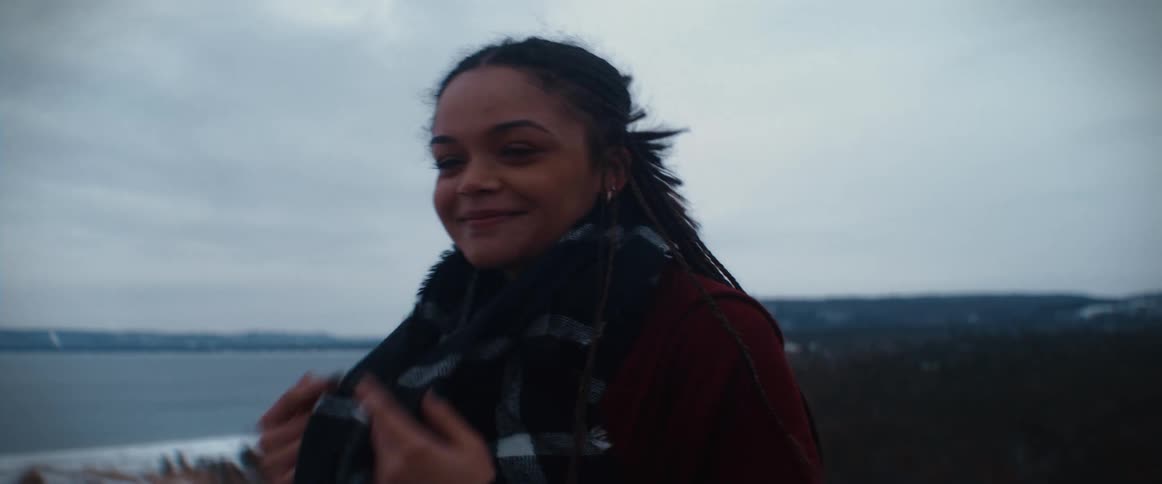 Young cold woman rubs her hands to warm them on a scarf close to the coast