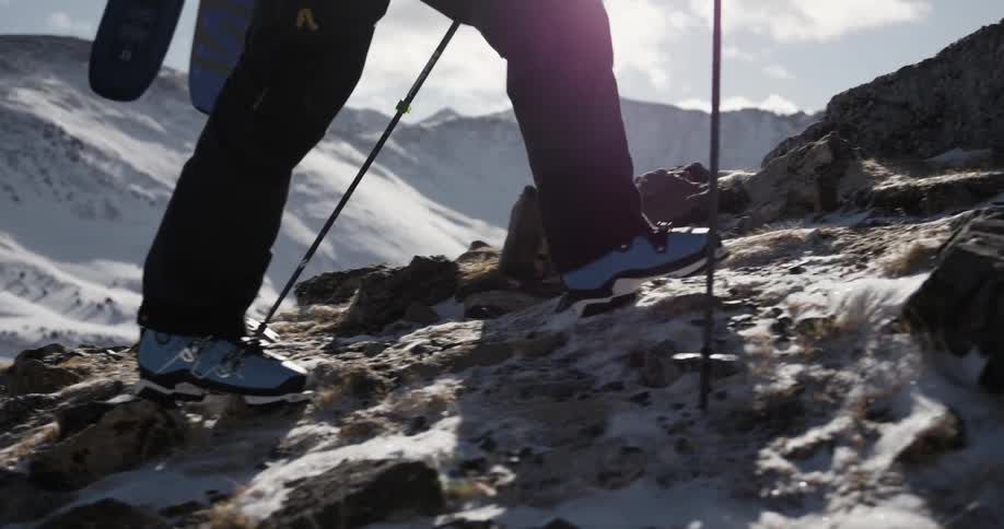 A skier hiking up a snowy mountainside on a winter day