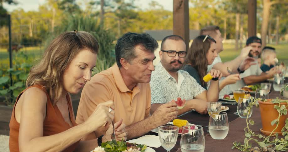 A family chats over lunch in a park