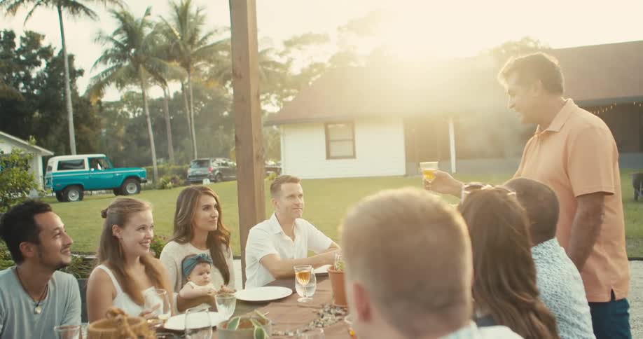 A man gives a toast to a table full of people outside