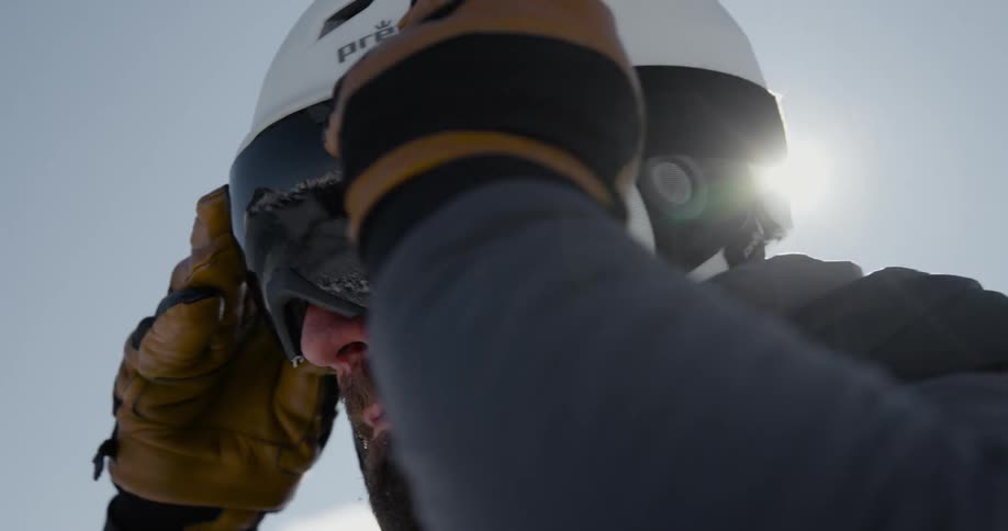 Man wearing helmet pulls down goggles under bright sun