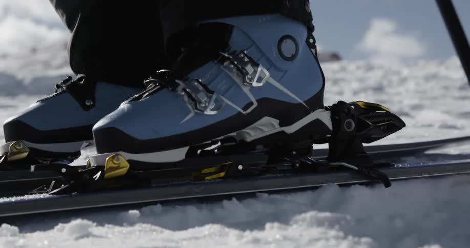 A person securing his boot on a snow ski over the snow