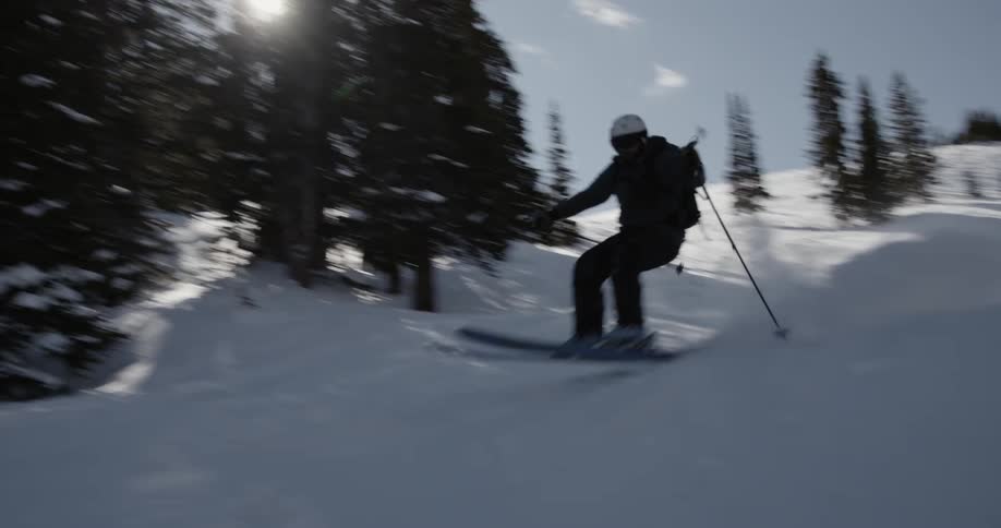 Man with helmet jacket and pants skies down mountain slope