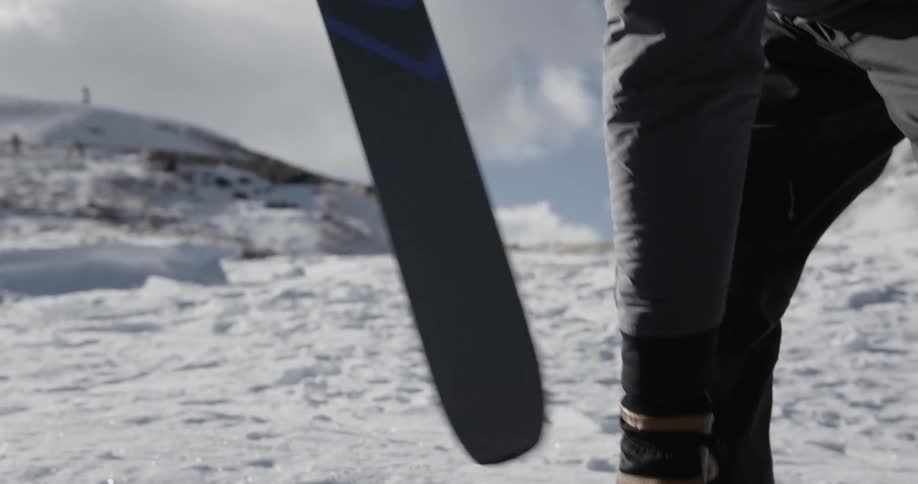 A man is putting on skiis outdoors in winter