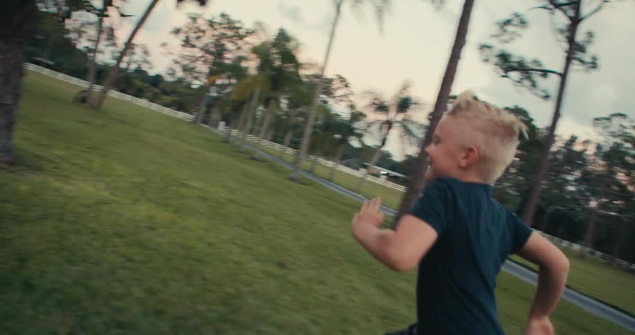 A boy laughs as he runs through a park