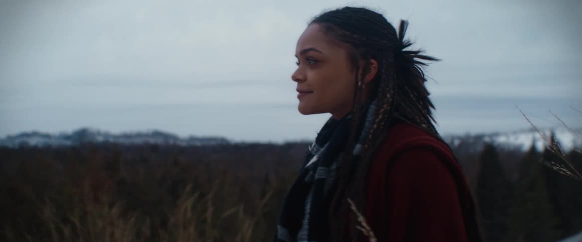 Woman bundled up for the cold stands looking around landscape with a smile