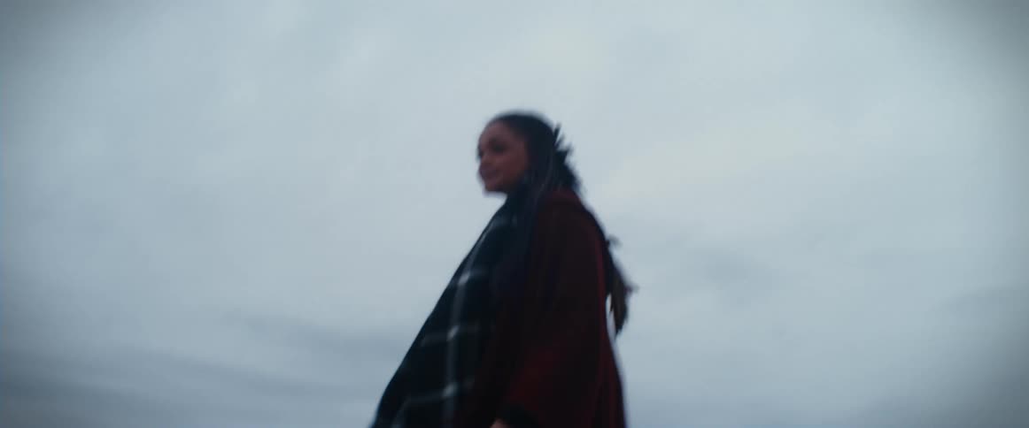 A woman runs to the edge of a cliff over the sea