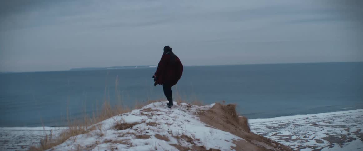 A woman is running on a hill near the coast of a beach in winter