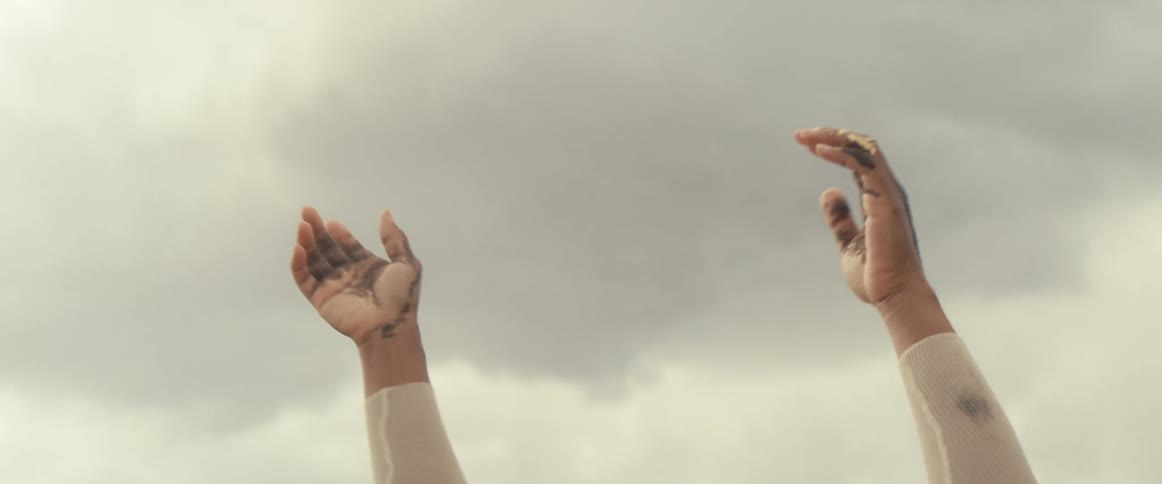 Person wearing tight sleeve while standing in desert reaches to the sky