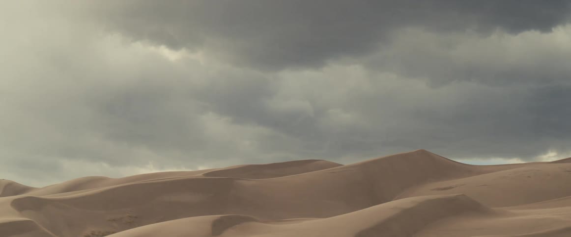 Dark clouds looming over sand dunes in the desert