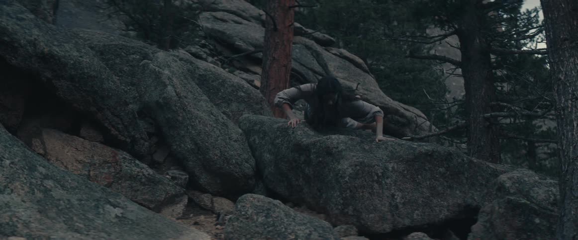 A woman crawls on the rock in pain