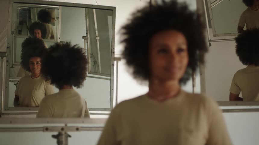 A portrait of a woman standing in a room full of mirrors