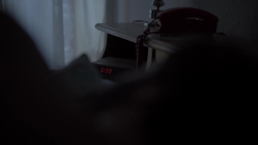 Person lies asleep near alarm clock