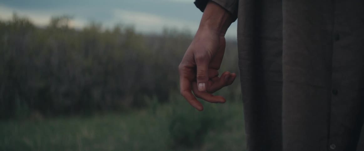 A persons hand adjusts position as the wind blows their shirt