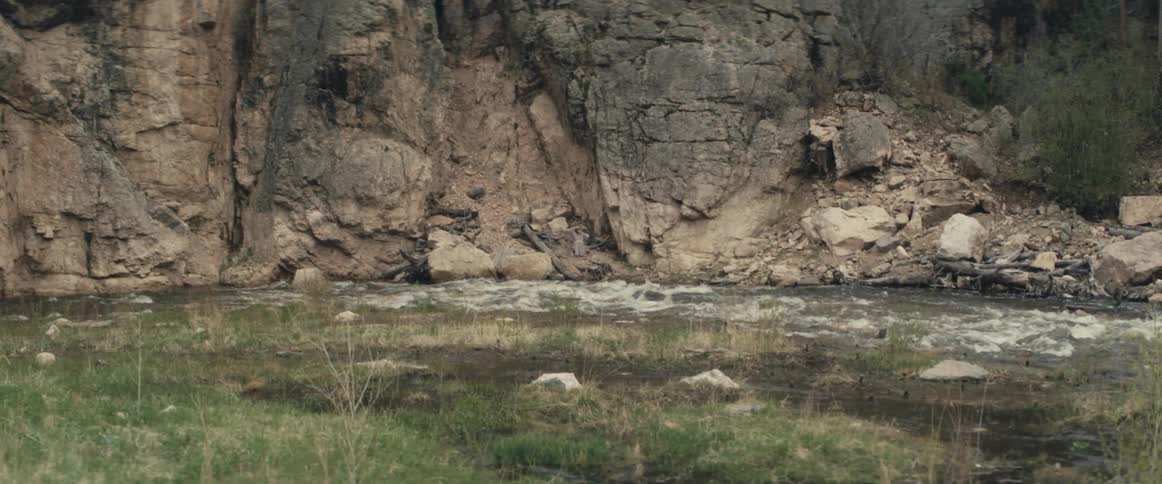 River flows past cliff and grass covered river bank
