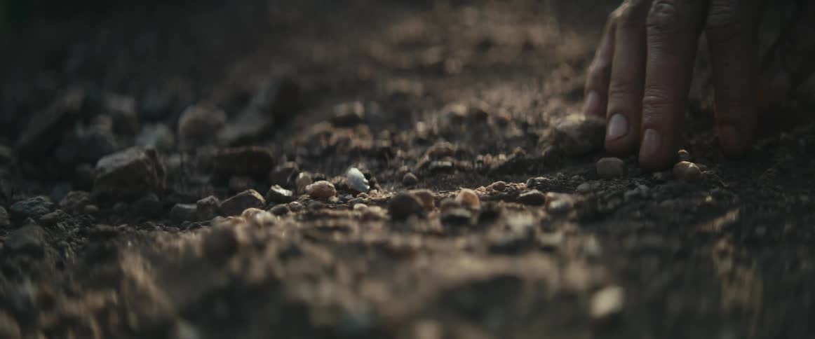 A person runs their fingers through the dirt