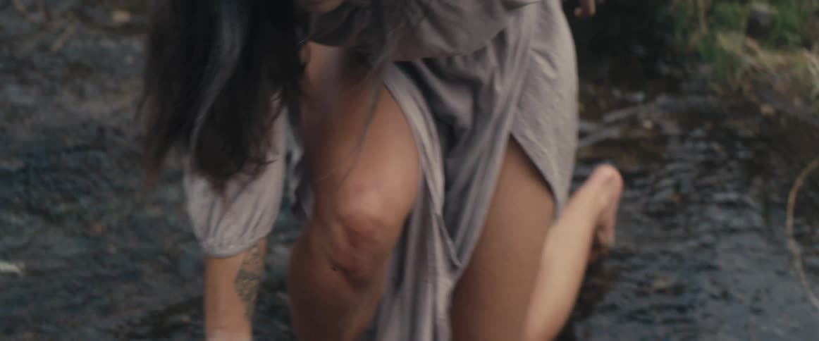 A womans eyes are covered in dirt as she digs in the stream