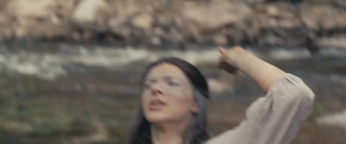 A woman is dancing near a river