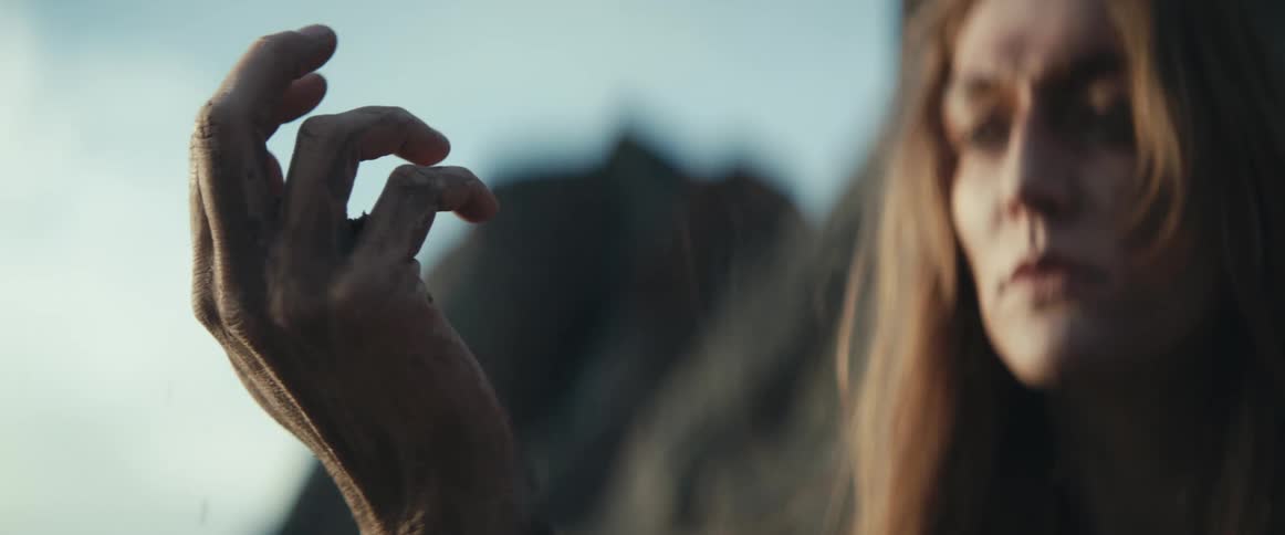 A woman slowly drops dirt from her hand