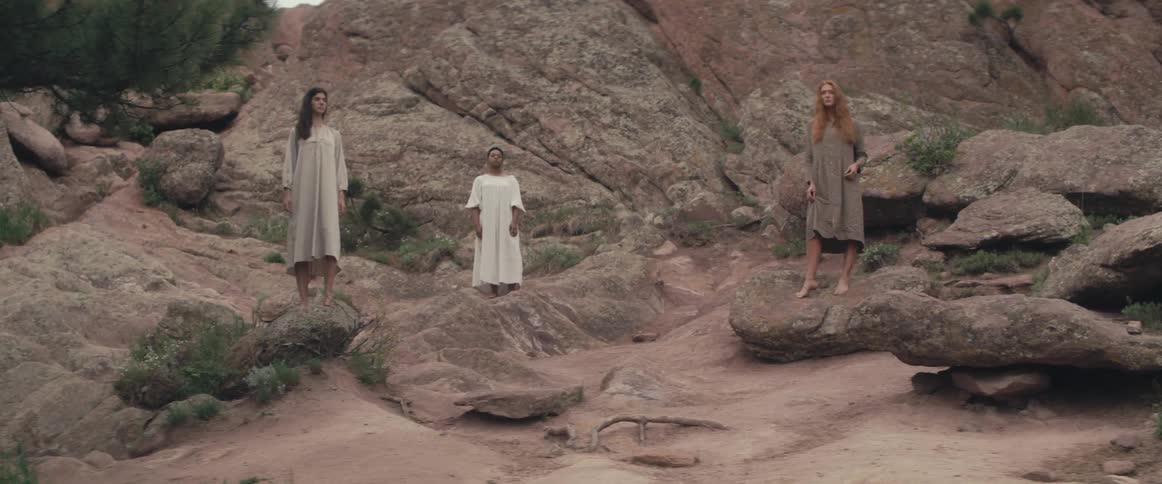 Three women stand on the rocks together