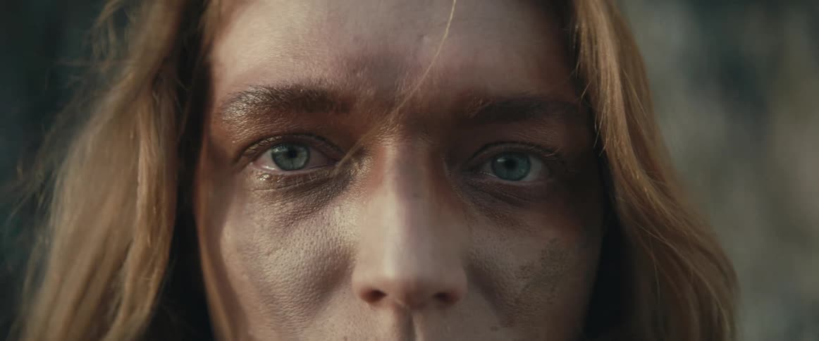 Blonde woman with blue eyed and muddy face looks at camera