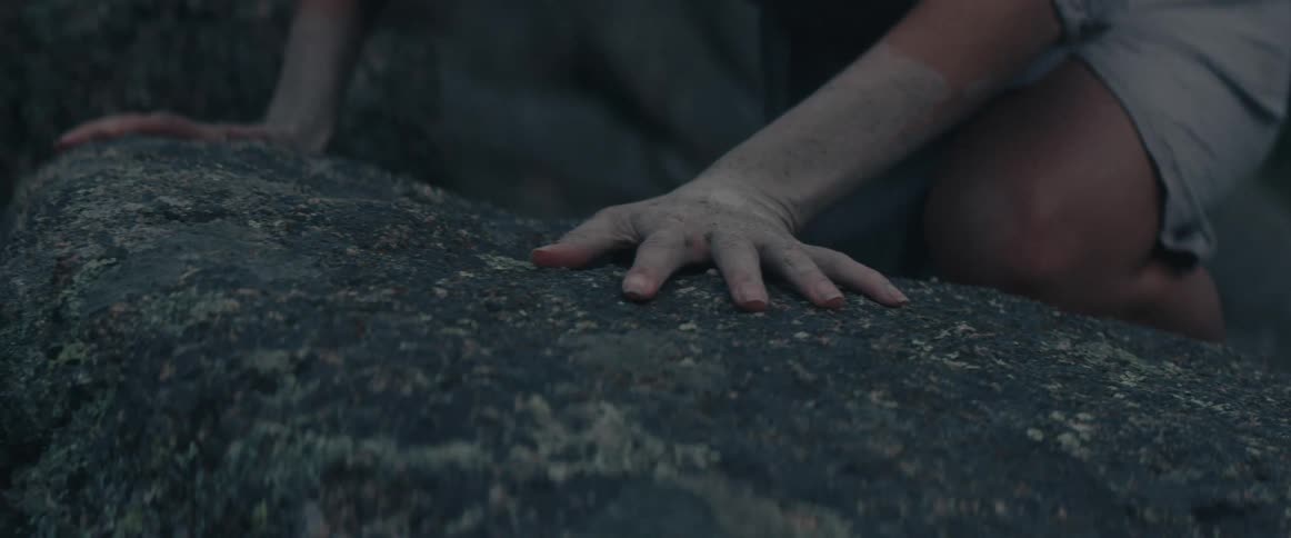A woman crawls on boulders in a forest
