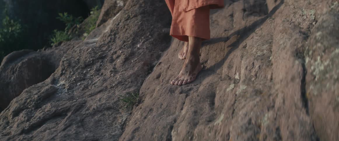 Womans dirty bare feet walking down a steep mountain side