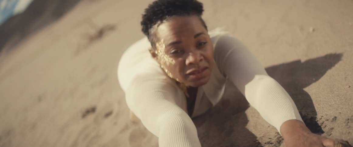 A woman reaches out for help as she crawls in the desert
