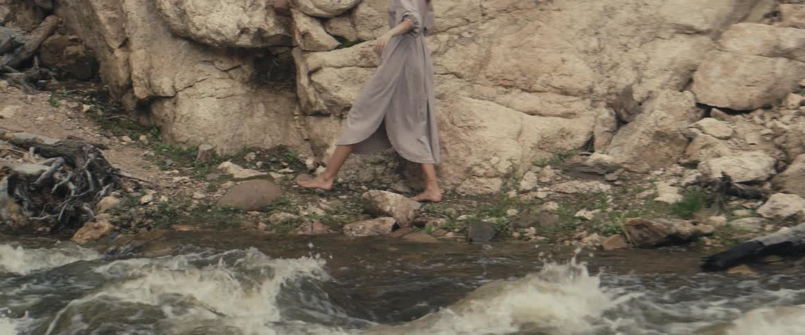 A woman walks along the stream