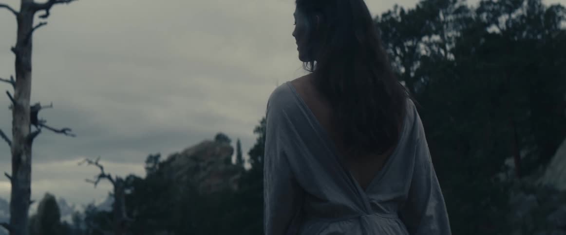 Woman stands outdoors looking around wilderness in valley