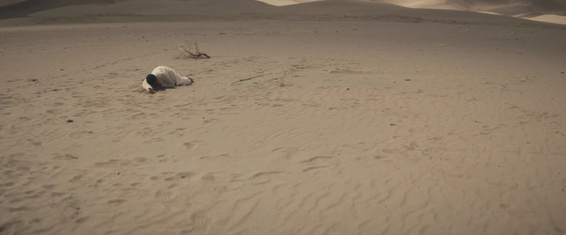 Woman with white dress lies on white sand in the desert