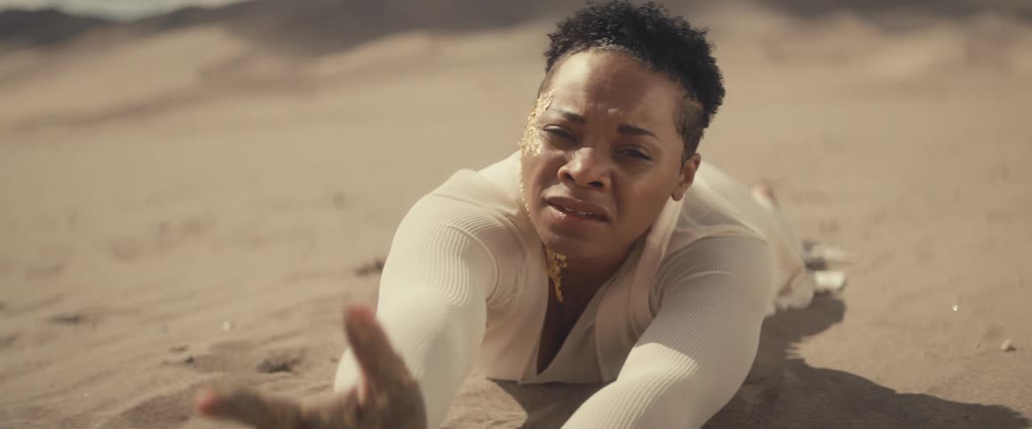 A woman is reaching out injured on the sand