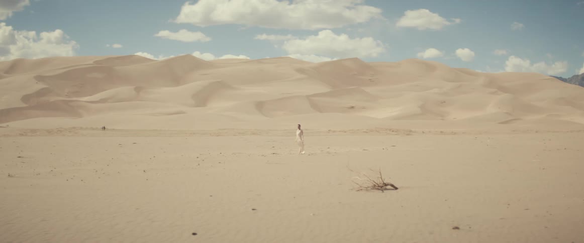 Woman with white dress stands on white sand desert