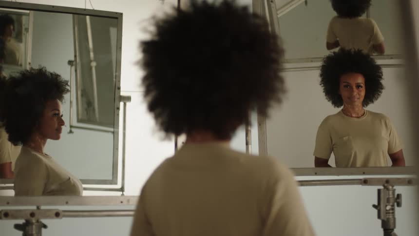 A woman looks into two bathroom mirrors and smiles