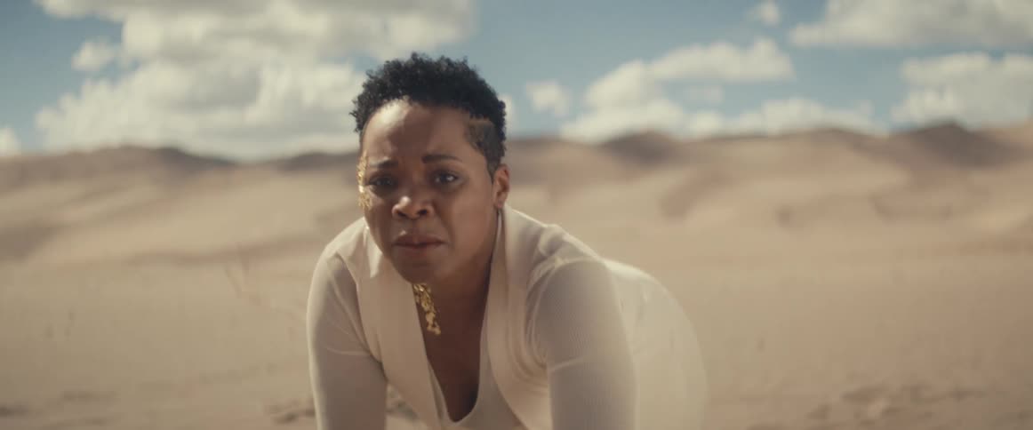 A tired worried woman crawls across the desert sand