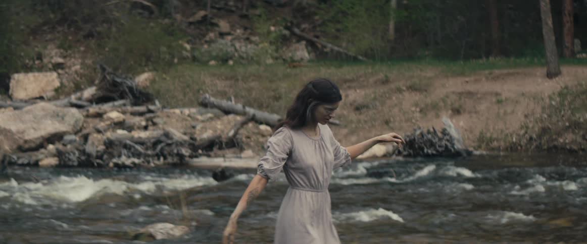 A woman runs her hands in the creek water