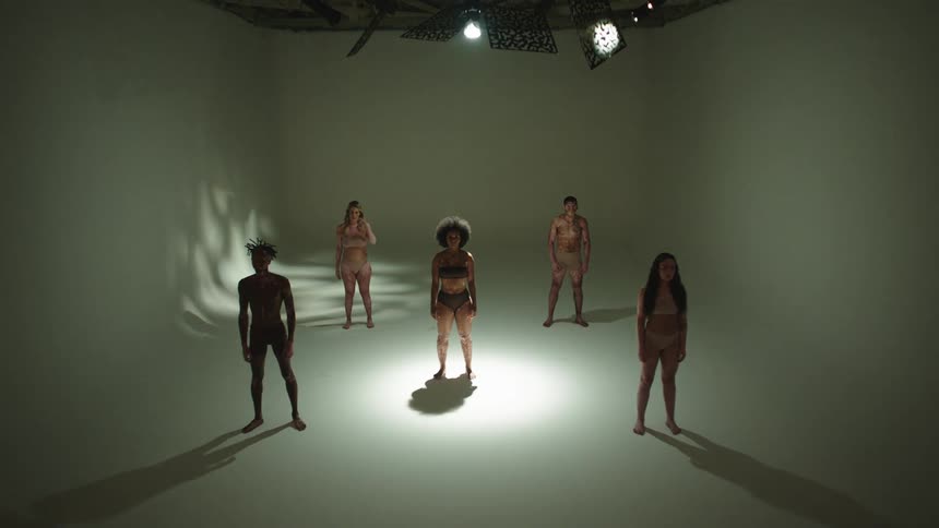 A group of five people in a studio with dramatic lighting