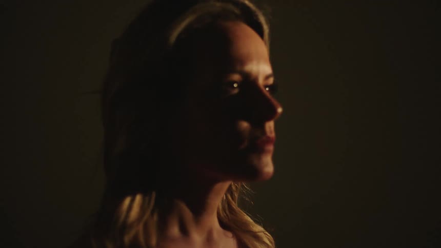 A woman stands under a flashing light indoors