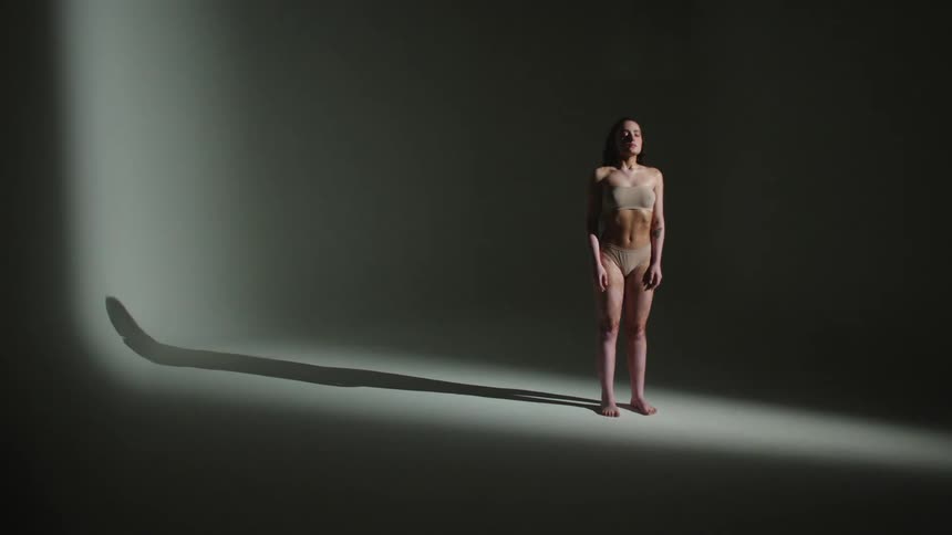 A model posing in a nude bra and underwear while the lights flash