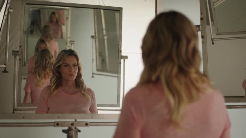 A woman is looking at her reflection in the mirror
